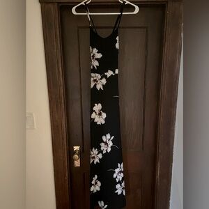 Black a-line maxi dress with flower detail and open cross cross back.